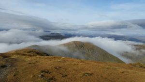 Eine schottische Berglandschaft ist zu sehen bei dem weiße Wolken über die Hänge ziehen